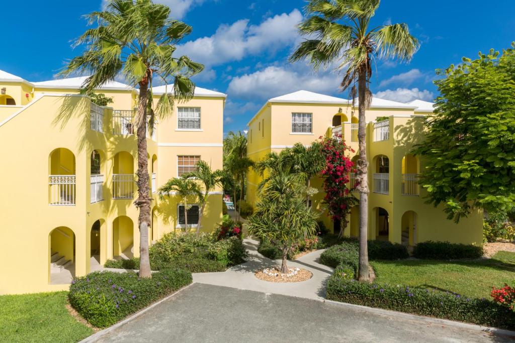 ein gelbes Gebäude mit Palmen und einer Auffahrt in der Unterkunft The Inn at Grace Bay in Grace Bay