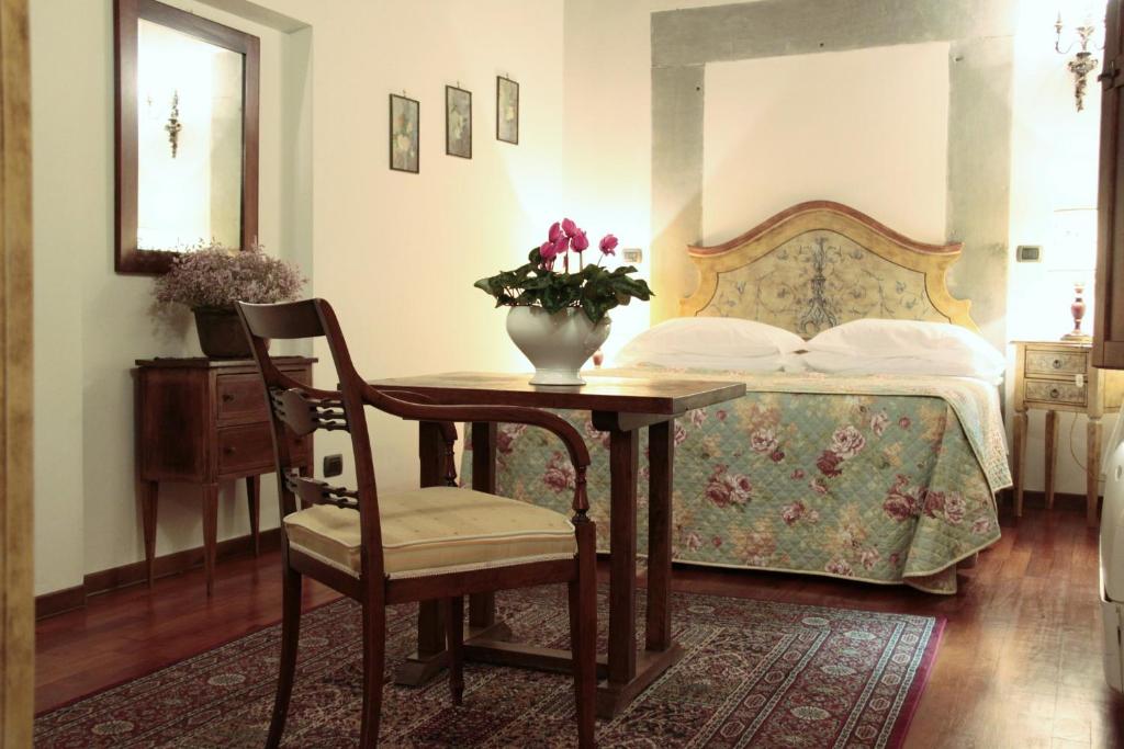 a bedroom with a bed with a table and a vase with flowers at Casa Del Vescovo in Florence
