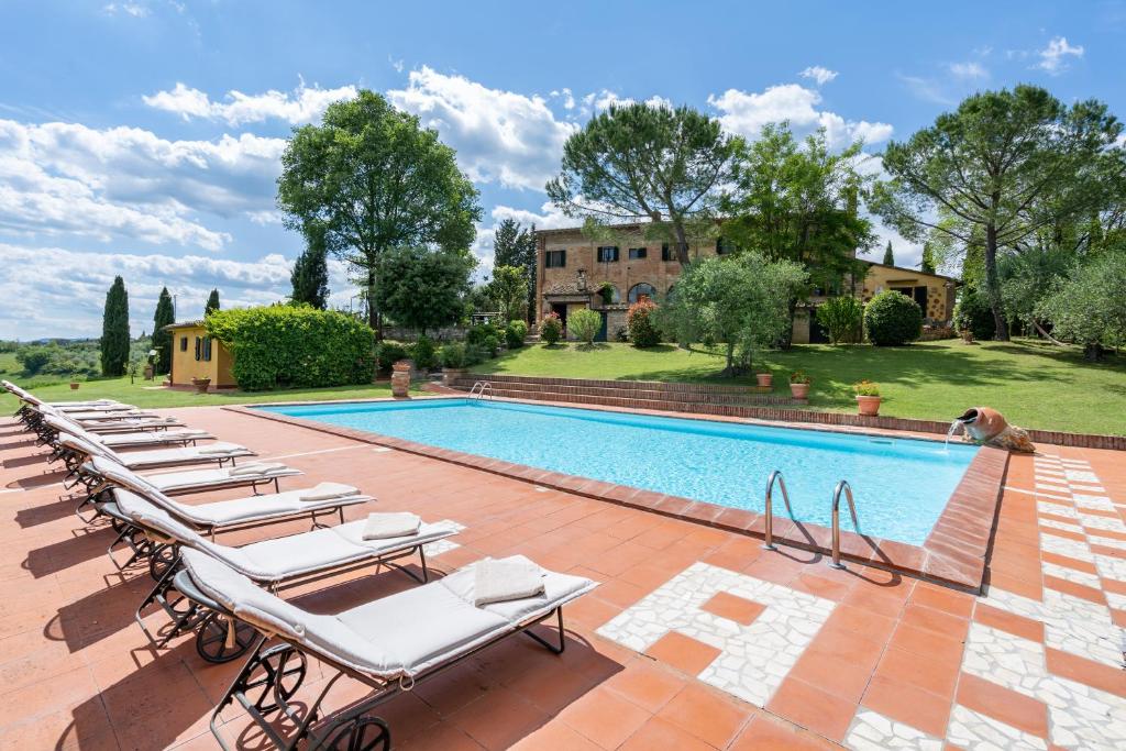 a row of lounge chairs next to a swimming pool at Il Palazzetto in Siena
