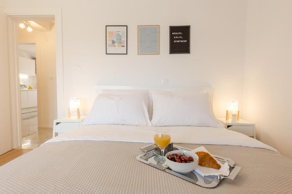 a bed with a tray of food and a bowl of fruit at Enjoy Split in Split