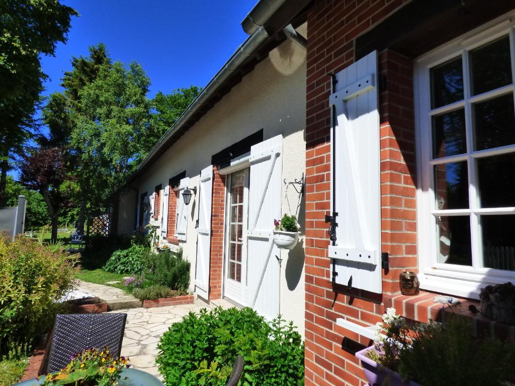 ceglany dom z białymi okiennicami i patio w obiekcie chambres d'hôtes les Muscaris w mieście Feins-en-Gâtinais