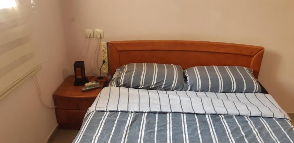 a bed with a wooden headboard and two pillows at Nik-rooms in Bat Yam