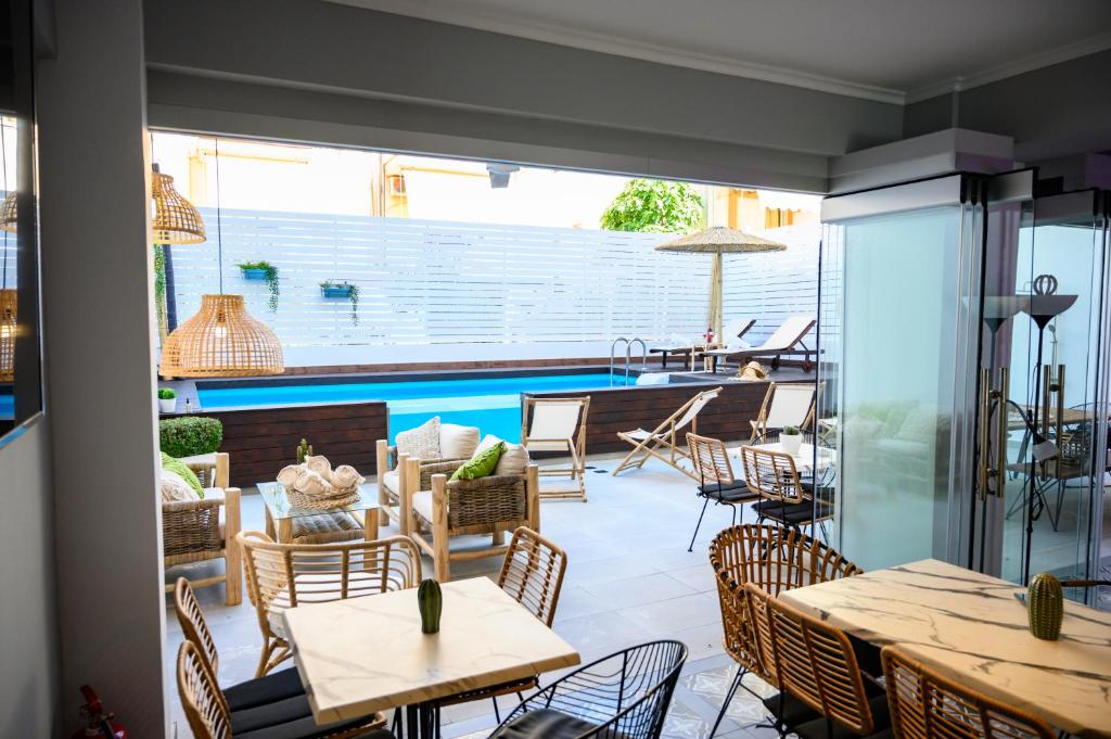 un patio con tavoli, sedie e piscina di Retro luxury rooms a Olympiakí Aktí
