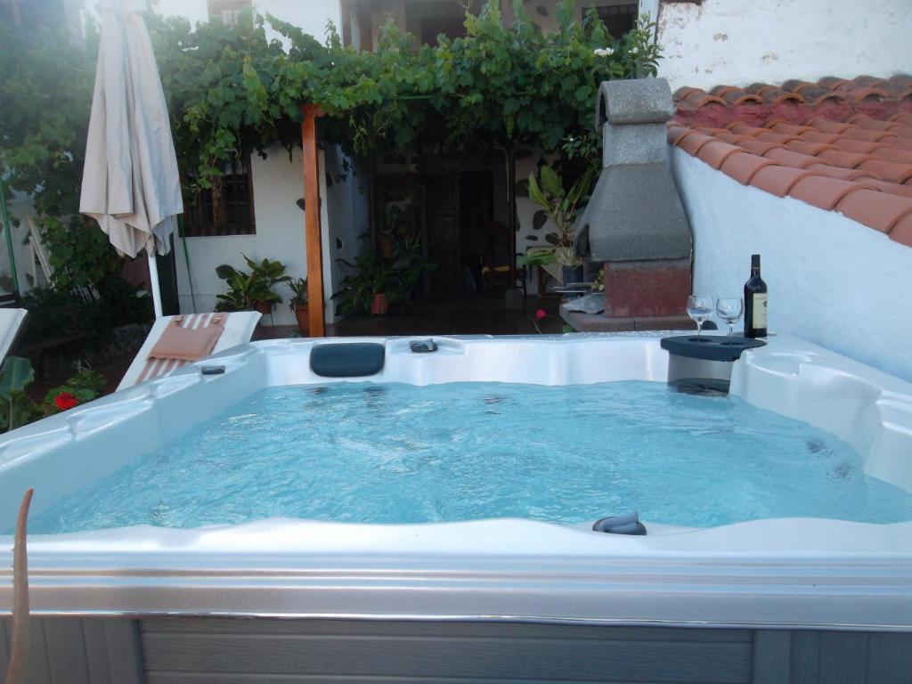 a hot tub on a patio with a bottle of wine at Casa Rural Guiniguada in Santa Brígida