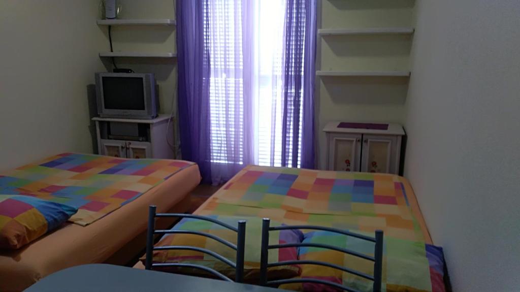um pequeno quarto com duas camas e uma televisão em Sunčani apartman 1-Vila Amfora em Budva