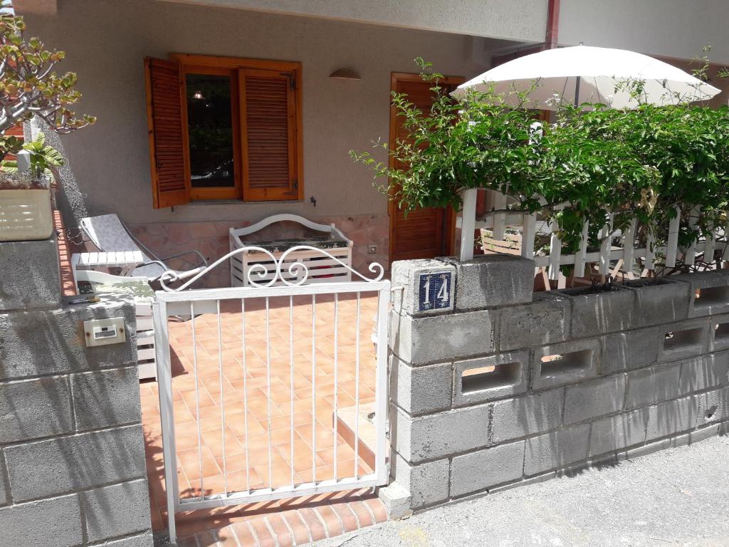 een poort naar een huis met een paraplu en een stoel bij Appartamento Airone in Piraino