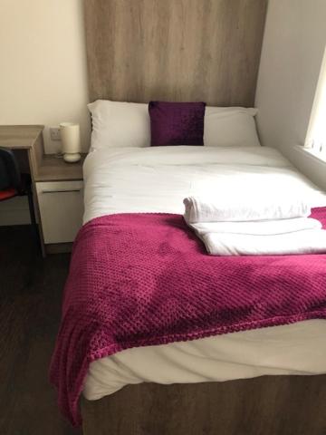 a bed with a purple blanket on top of it at Lancaster Studio Apartments in Leicester