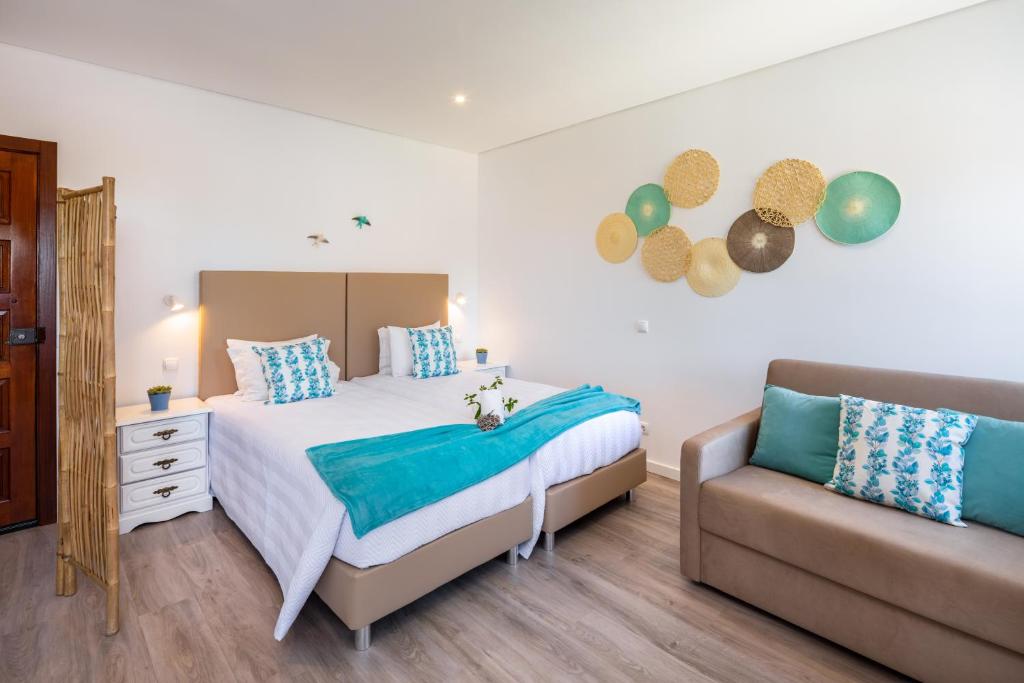 a bedroom with a large bed and a couch at Apartamentos Flor da Laranja, Albufeira in Albufeira