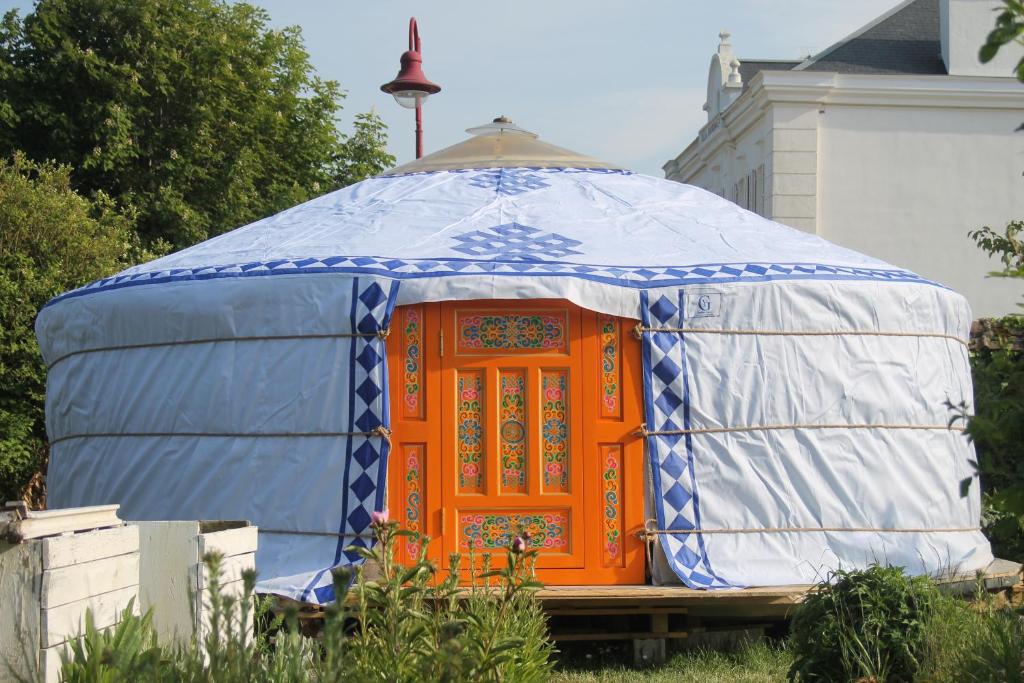 una yurta con una porta arancione seduta in un cortile di Yourte Grain de Folie a Waben