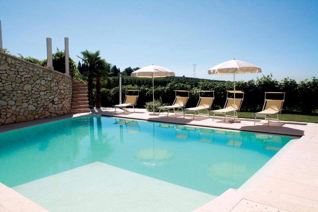 una piscina con sillas y sombrillas en B&B Al Cristo, en SantʼAmbrogio di Valpolicella