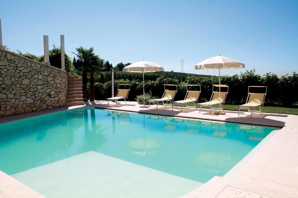 una piscina con sedie e ombrelloni di B&B Al Cristo a SantʼAmbrogio di Valpolicella