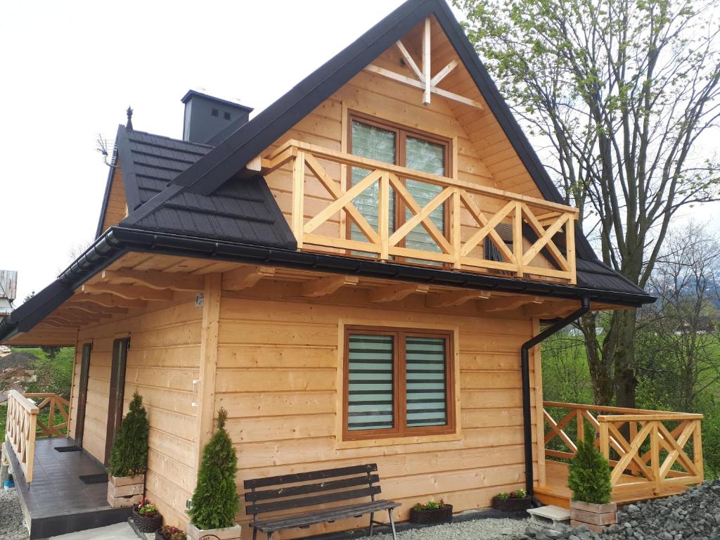 ein Blockhaus mit einem schwarzen Dach und einer Veranda in der Unterkunft Domki "Na Ugorach" Apartamenty in Zakopane