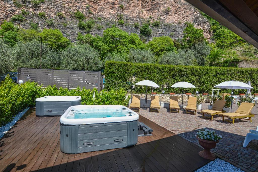 a hot tub on a deck with chairs and umbrellas at Villa degli Olivi Relais in Nago-Torbole