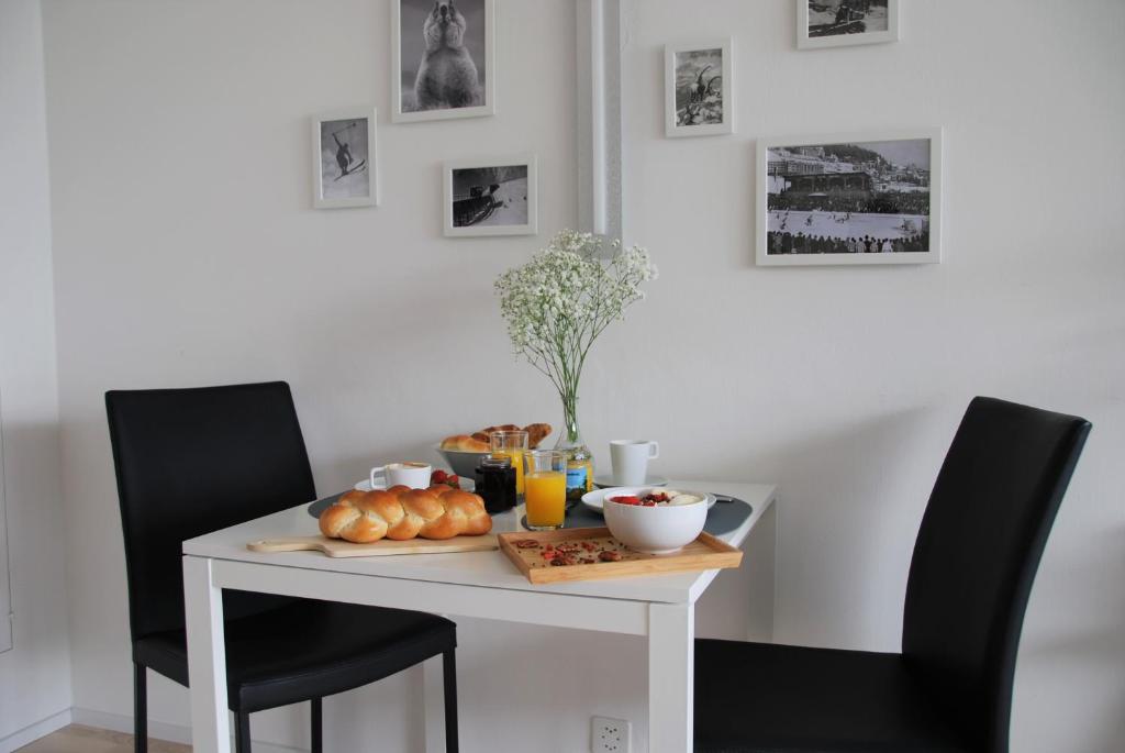 Davos Holiday Apartment في دافوس: طاولة بيضاء مع كراسي سوداء والطعام عليها