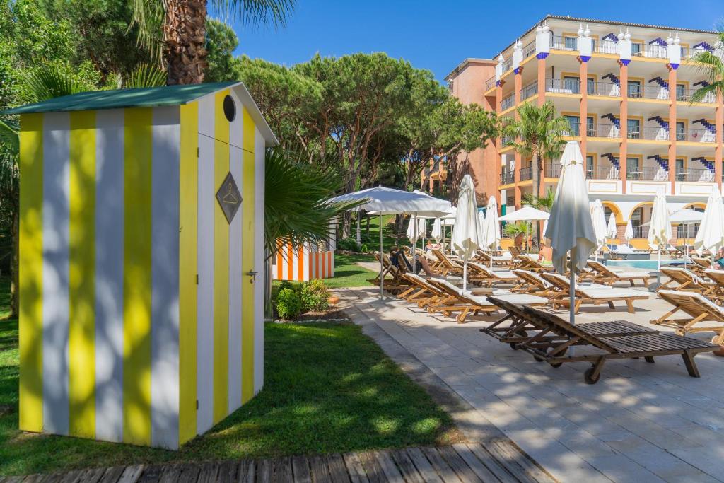 a yellow and white building with chairs and umbrellas at TUI Blue Isla Cristina Palace - Adults Recommended in Isla Cristina