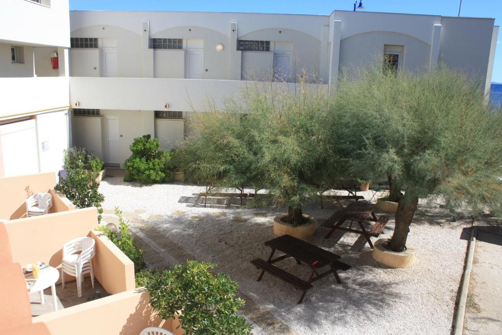 an apartment patio with tables and trees in front of a building at Les Stoechades in Hyères