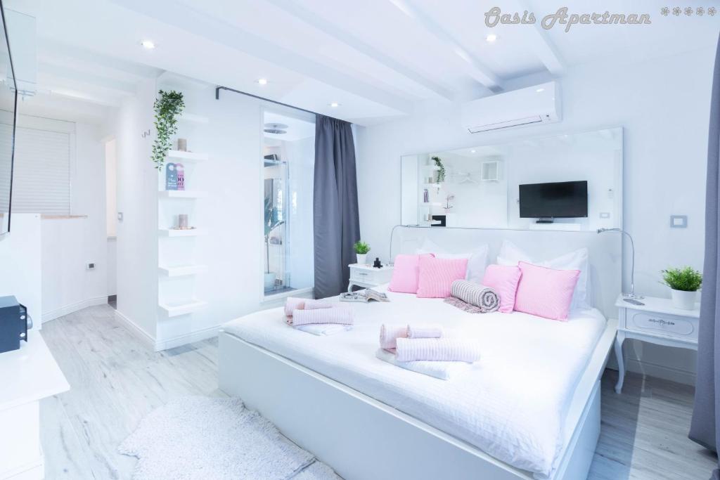 a white bedroom with a large white bed with pink pillows at Oasis Apartments Opatija in Opatija