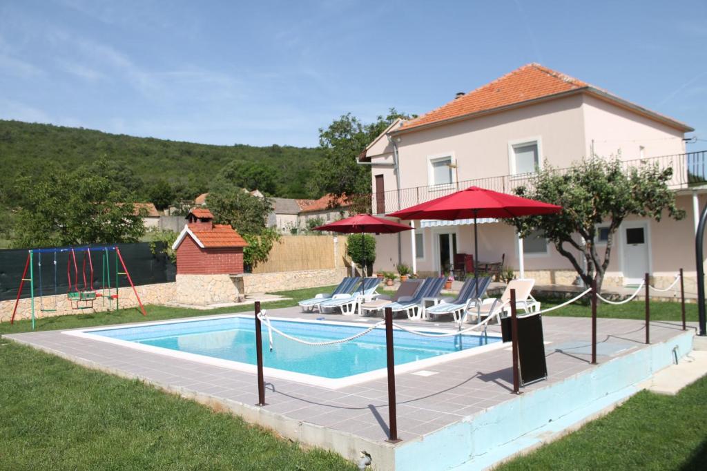 a house with a swimming pool with chairs and umbrellas at Holiday home Miramary in Trilj
