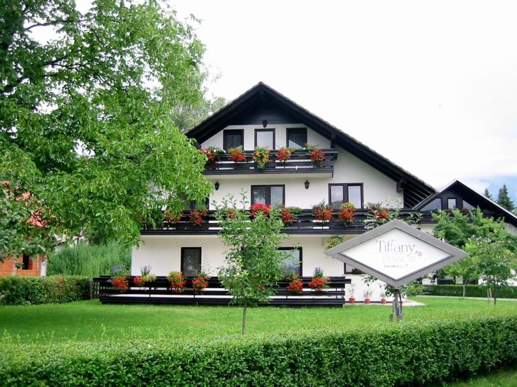 une grande maison blanche avec un panneau devant elle dans l'établissement Tiffany Pension Bled, à Bled