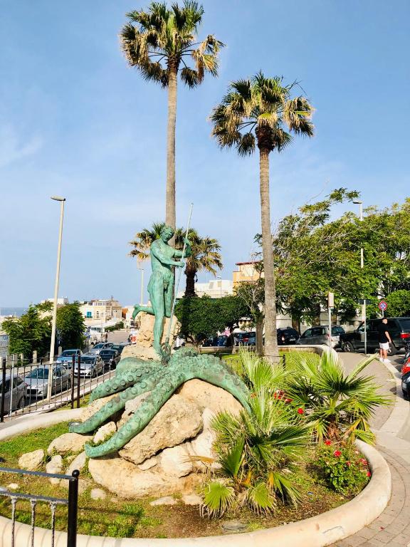 a statue of a man standing on a rock with palm trees at Relax House in Bari