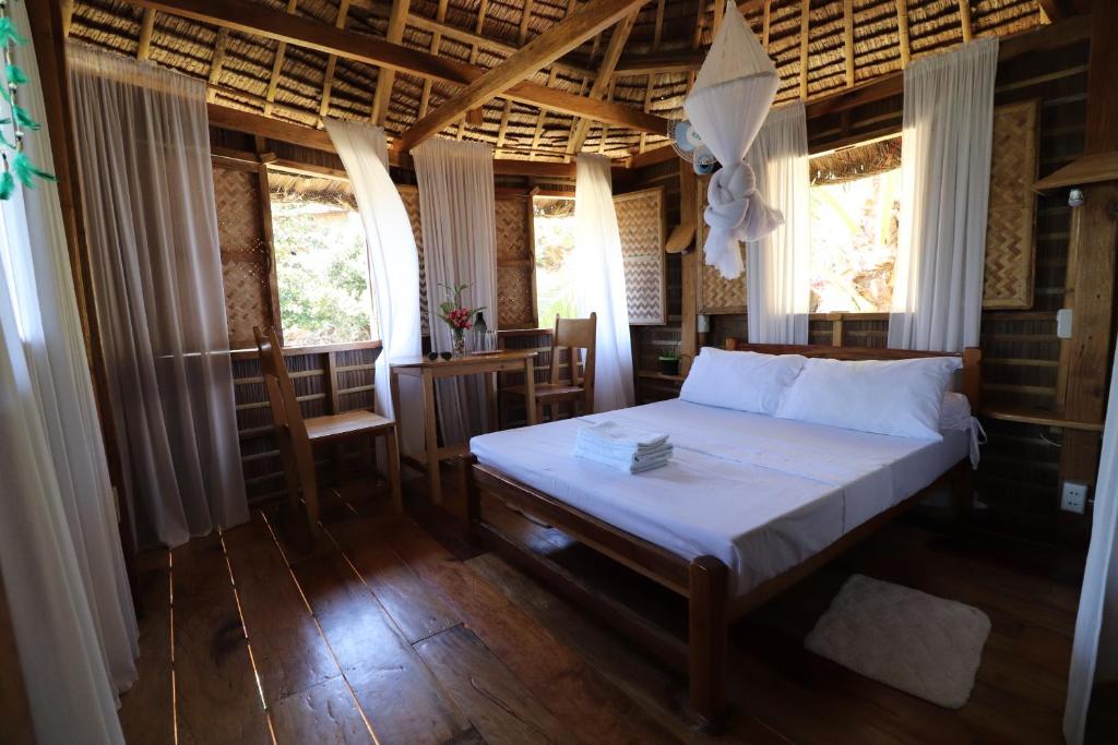 a bedroom with a bed in a room with windows at Tinaoog Beach Resort in Romblon