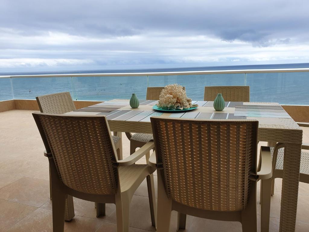 una mesa con sillas y un plato de comida en el balcón en Departamento frente al mar en Manta-Barbasquillo con espectacular vista, en Manta