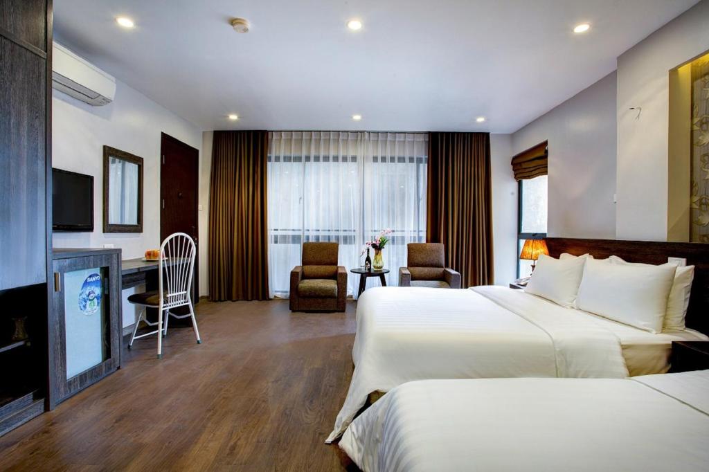 um quarto de hotel com duas camas e uma secretária em My Linh Hotel em Hanói