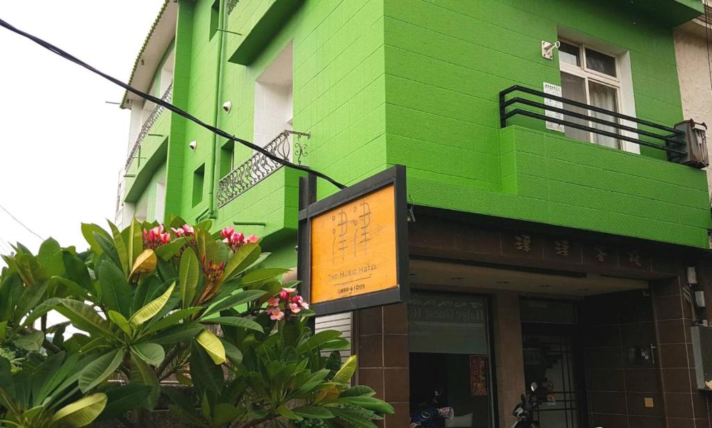 un bâtiment vert avec un panneau devant lui dans l'établissement Kenting Jinjin Music Inn, à Kenting