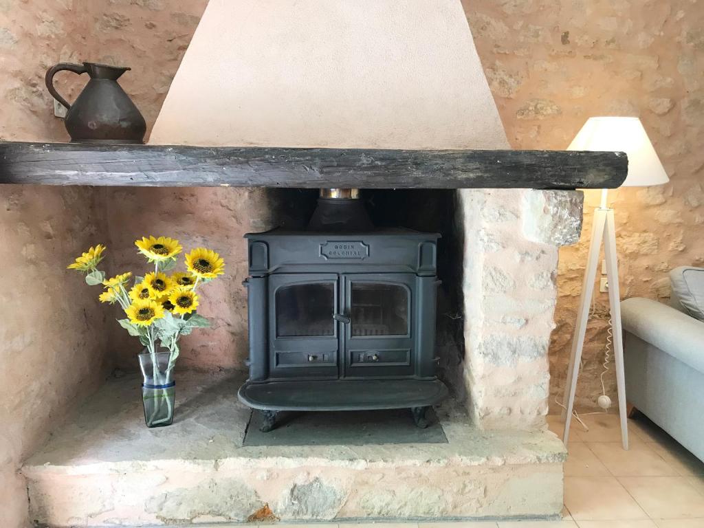 a stove in a room with a vase of flowers at Hameau de Montcabirol - Foix in Mirepoix