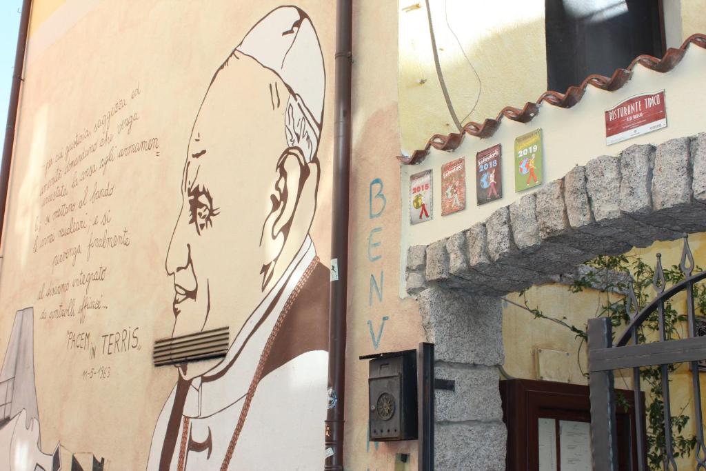 b&b il Portico Orgosolo في أورغوسولو: لوحة جدارية لرجل مع لوح ركوب الأمواج على مبنى