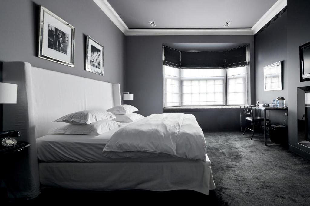 a bedroom with a bed with white sheets and a window at Hotel Odette en Ville in Brussels