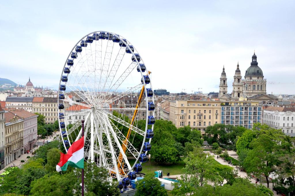 a ferris wheel in front of a city at City Corso Apartman in Budapest