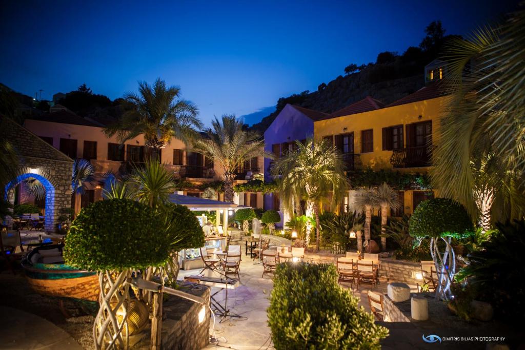 an outdoor patio with chairs and trees at night at Iapetos Village in Symi