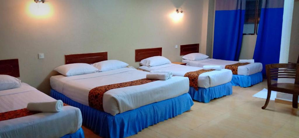 a hotel room with four beds in a room at Hotel K T Mutiara in Kuala Terengganu
