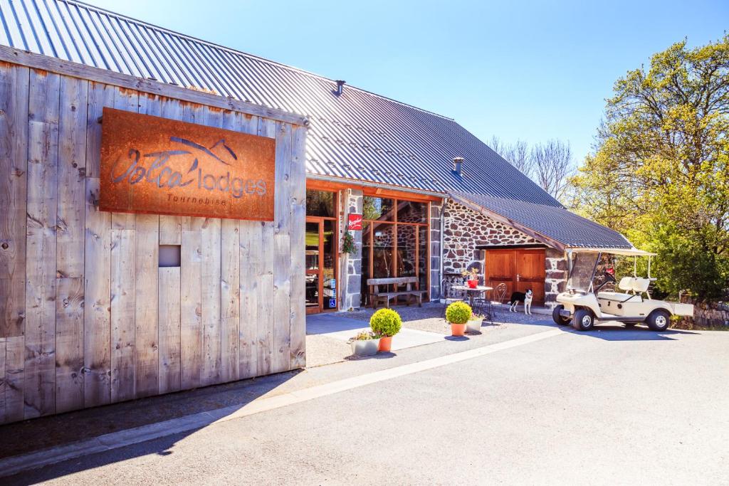 an old car parked outside of a barn with a building at Les Volca'lodges de Tournebise in Saint-Pierre-le-Chastel