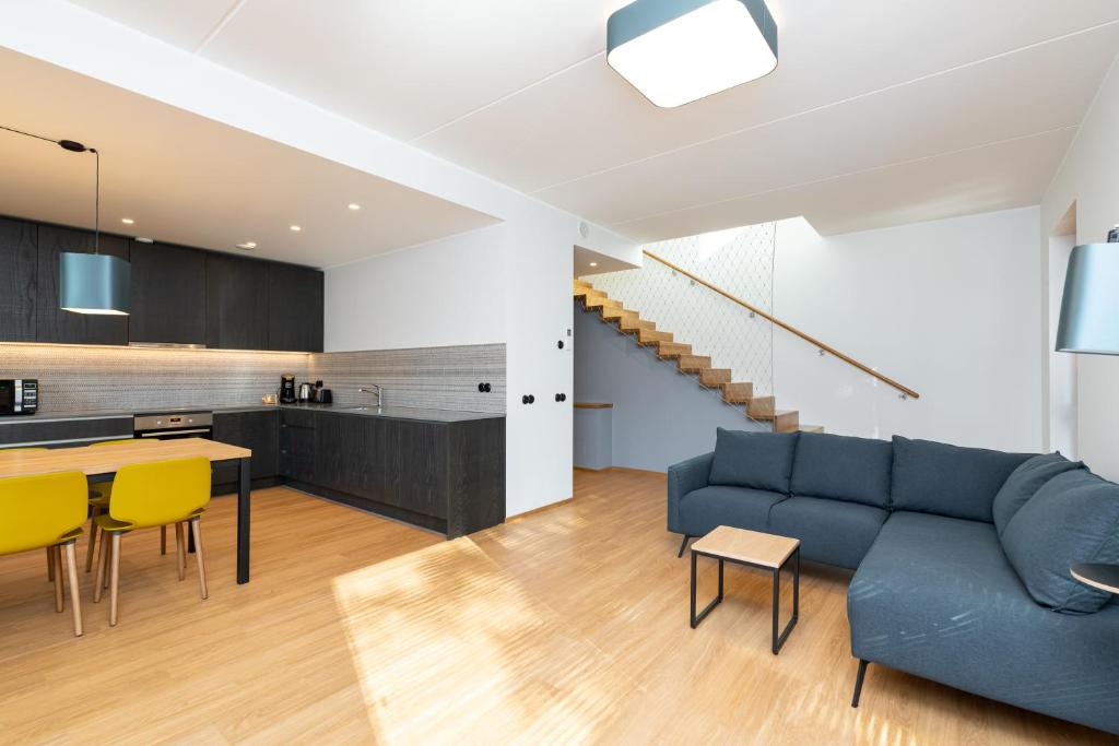 a living room and kitchen with a blue couch and yellow chairs at Self-check-in 3 bedroom apartment with sauna and balconies in Tallinn