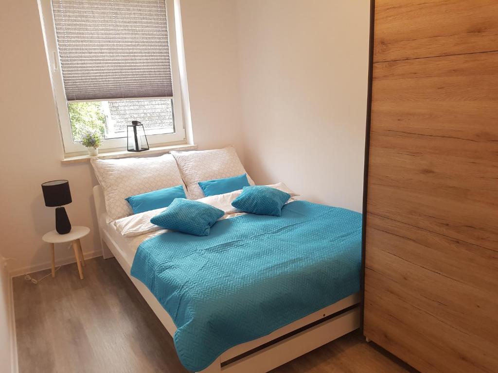 a bedroom with a bed with blue sheets and a window at Narutowicza Modern Apartment in Słupsk