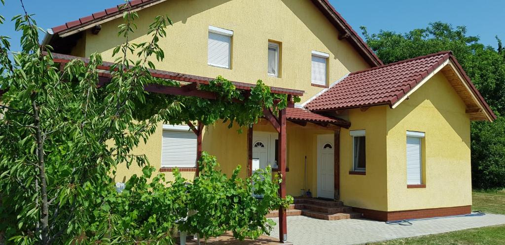 a yellow house with a tree in front of it at Pataki House in Mórahalom