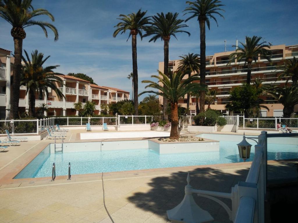 a swimming pool with palm trees and a building at Open Residence Golfe Juan in Vallauris