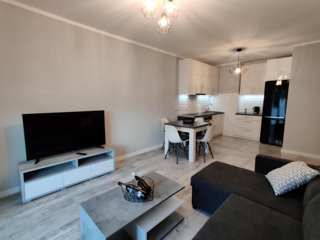a living room with a couch and a tv and a table at Mazurski Apartament in Mrągowo