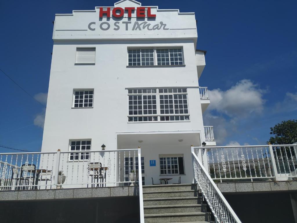 um edifício branco com um cartaz em Hotel costa mar em Sanxenxo