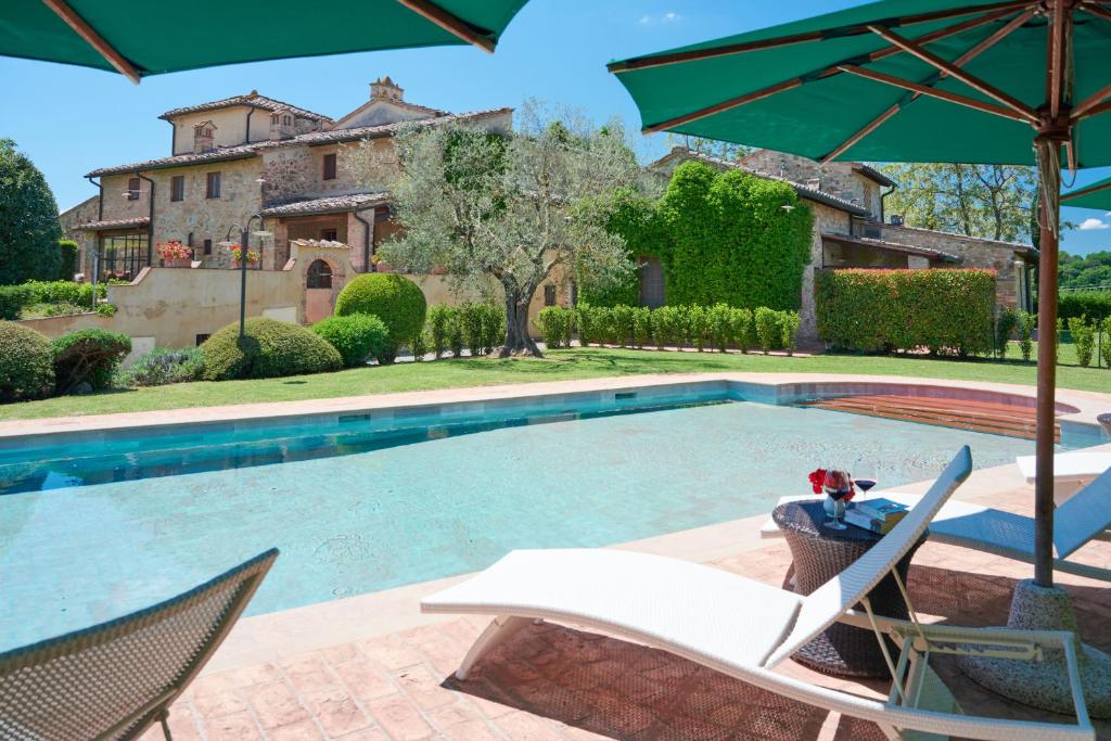 a pool with chairs and an umbrella and a house at Santa Maria a Poneta in Barberino di Val dʼElsa