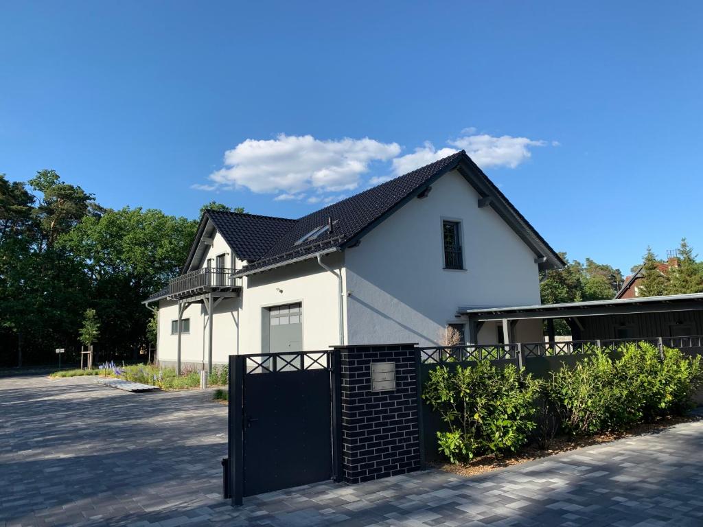 ein weißes Haus mit einem schwarzen Zaun davor in der Unterkunft Dreihof Brandenburg in Stülpe