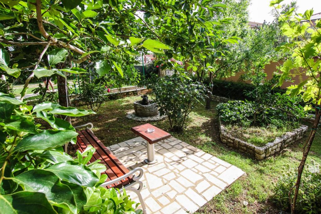 a garden with a bench and a table and trees at Apartments Vuceric in Peroj
