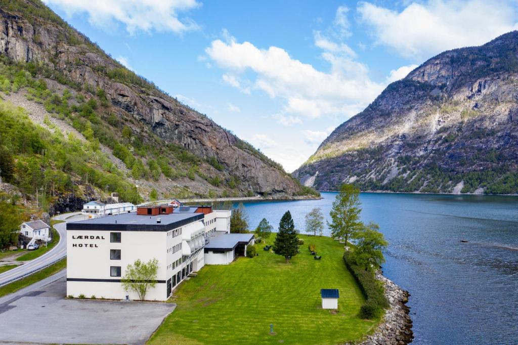 a building on the side of a lake with mountains at Lærdal Hotel in Lærdalsøyri