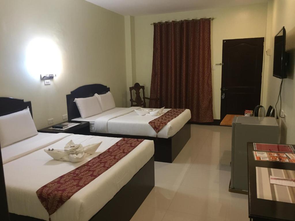 a hotel room with two beds and a window at Hollywood Suites in General Santos