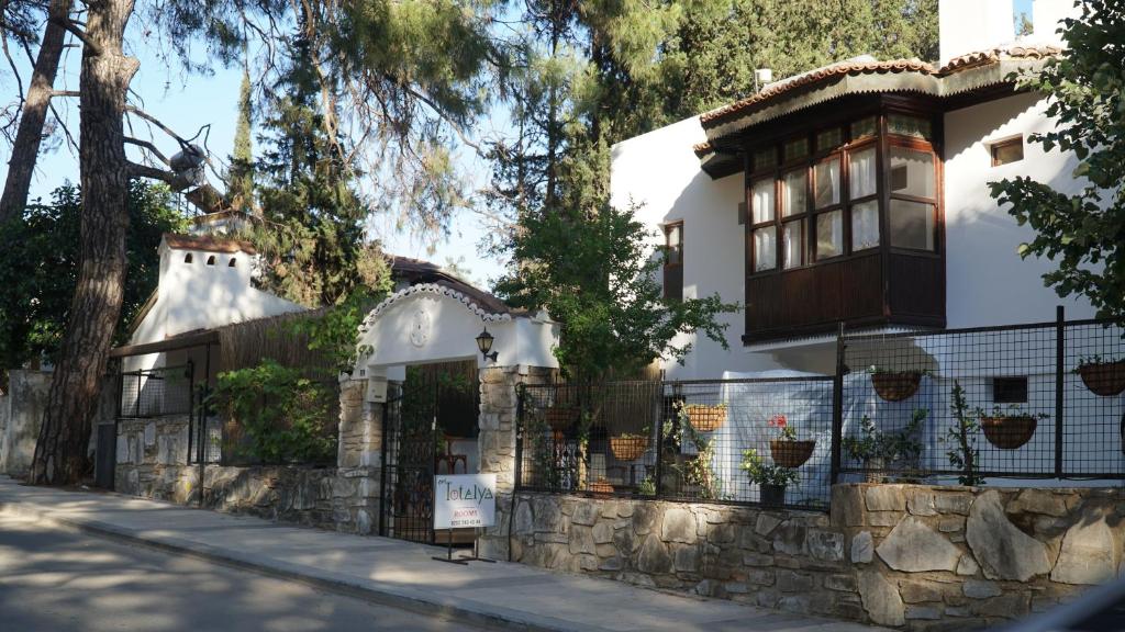 una casa blanca con una valla y árboles en Totelya Hotel, en Akyaka