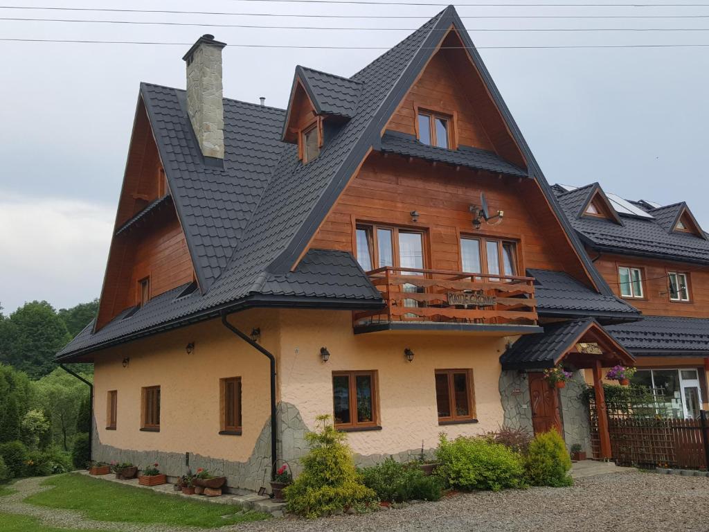 a large wooden house with a black roof at POD ROŻKAMI in Cisna