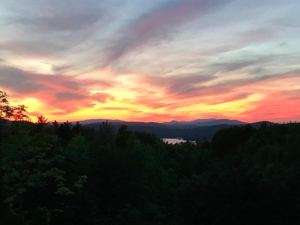 a sunset in the mountains with trees in the foreground at Ballard House Inn in Meredith