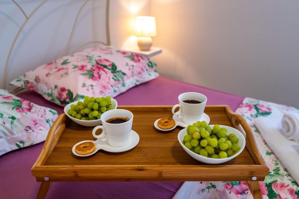 a tray with cups of coffee and bowls of fruit on a bed at Apartman ZOZZY in Posedarje